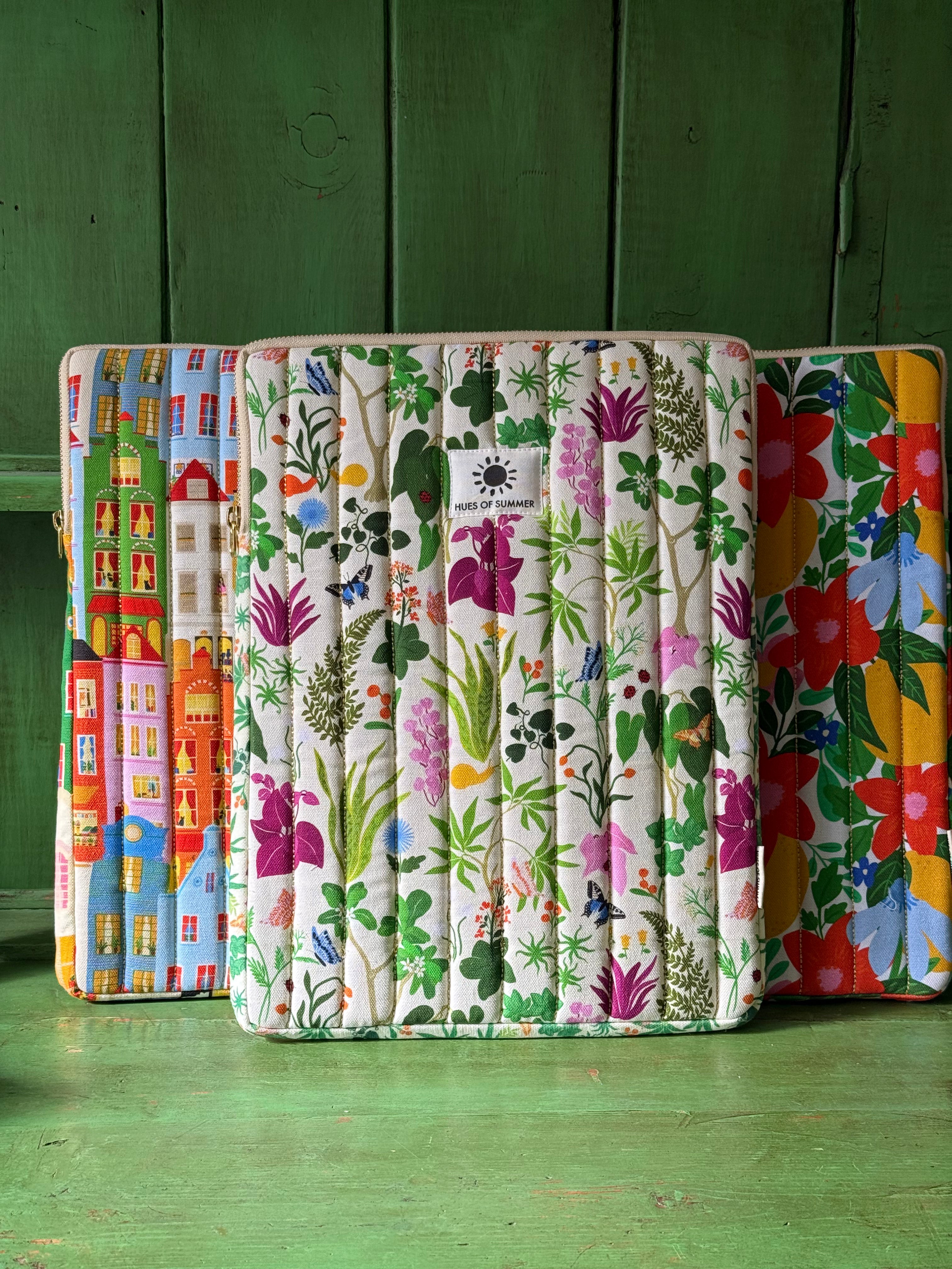 Bugs and Bloom quilted laptop sleeve displayed with an Amsterdam and a floral quilted sleeve
