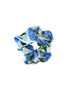 A fabric hair scrunchie with a blue and green floral print on a white background, placed on a wooden surface.