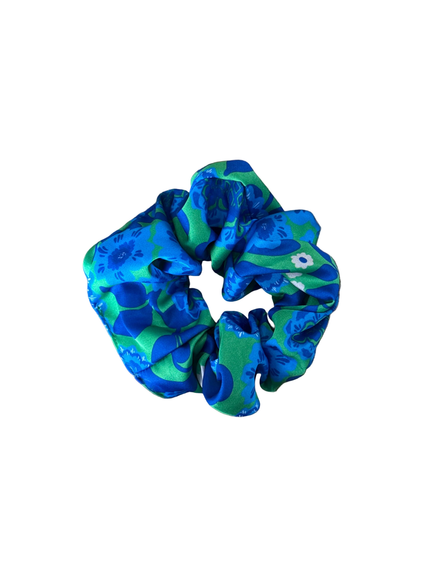 A fabric hair scrunchie with a blue and green abstract pattern, placed on a wooden surface.