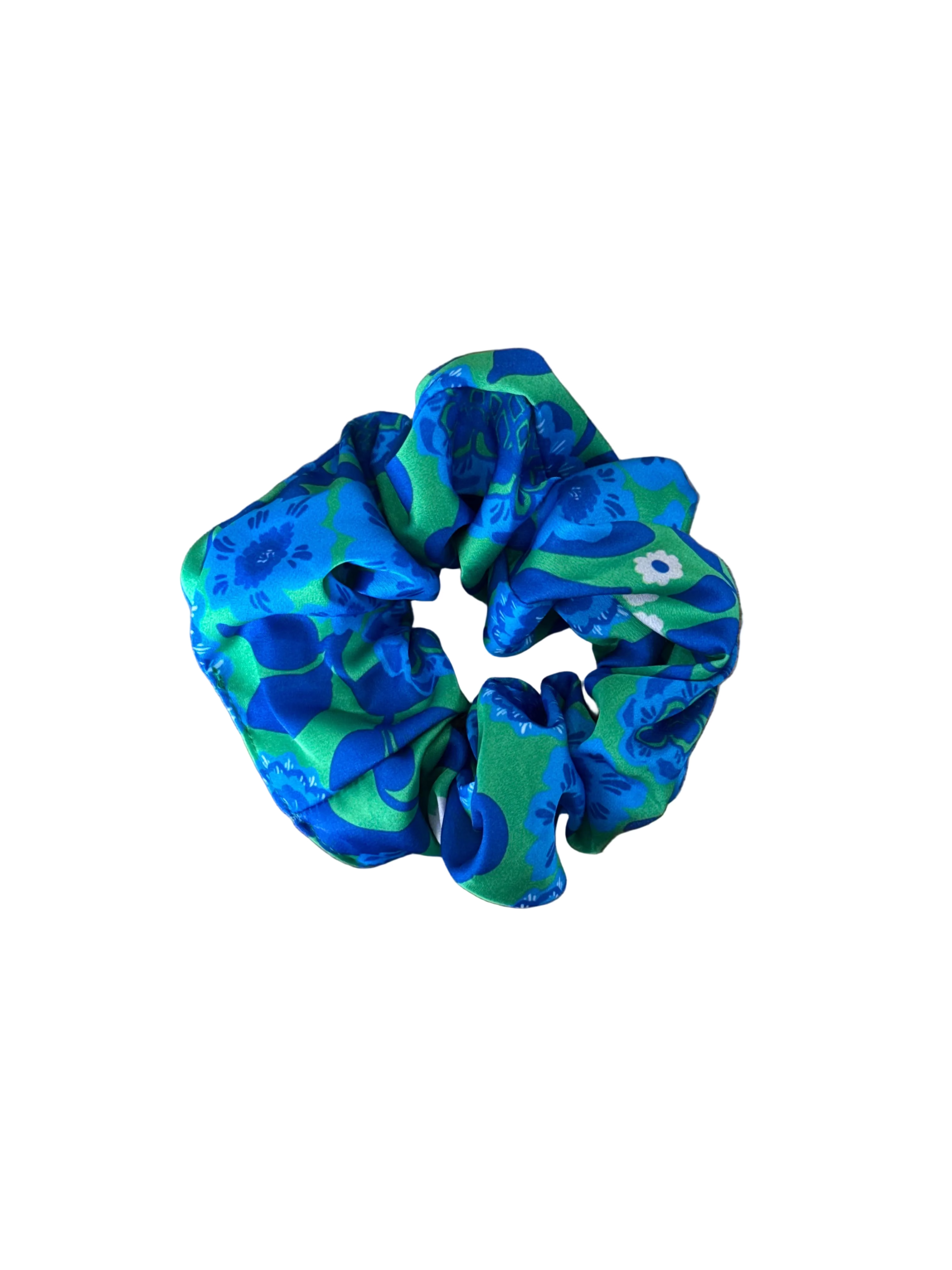 A fabric hair scrunchie with a blue and green abstract pattern, placed on a wooden surface.