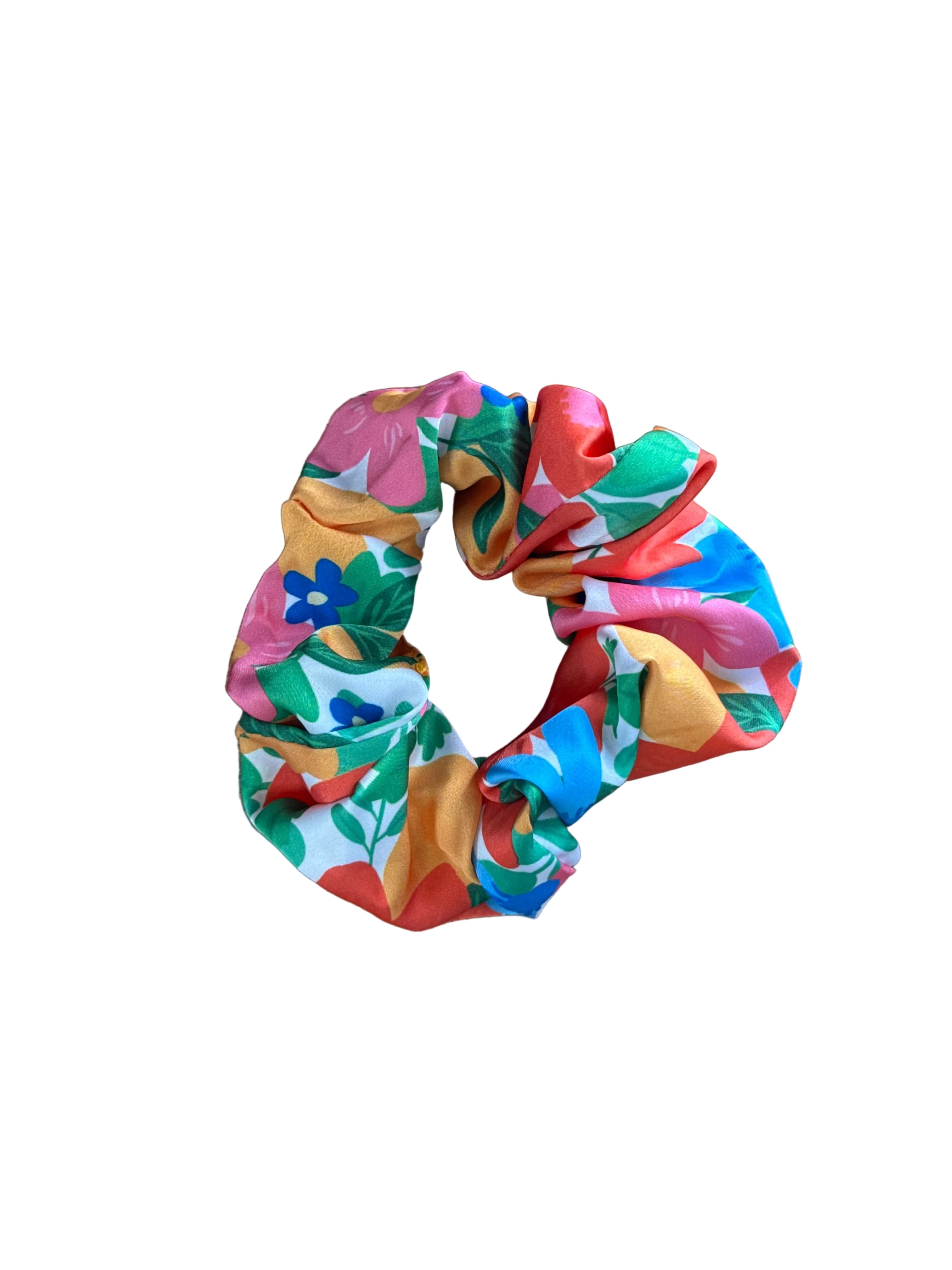 A colorful fabric scrunchie with a retro floral pattern, placed on a light brown wooden surface.