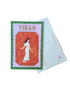 A vintage-style Virgo postage stamp card featuring an illustration of a woman in a white dress on an orange-red background, bordered in green and pink, placed on top of a white postcard on a wooden table.