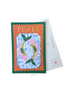 A Pisces zodiac-themed postcard with a colorful fish illustration and orange border, displayed on a wooden table next to a white postcard envelope.