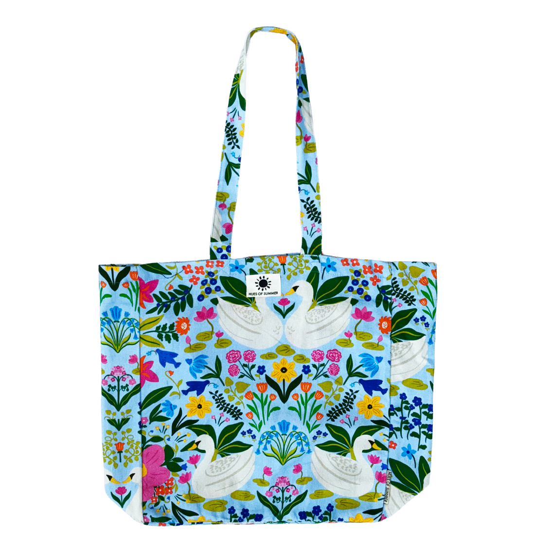 Lake Side Swans tote bag laid flat, showing two white swans among florals on light blue fabric